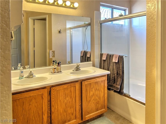 full bath featuring double vanity, enclosed tub / shower combo, a sink, and tile patterned floors