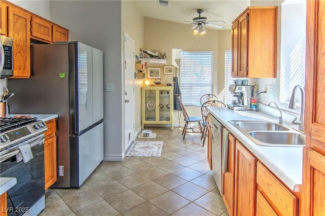 kitchen featuring stainless steel appliances, a wealth of natural light, light countertops, brown cabinetry, and a sink