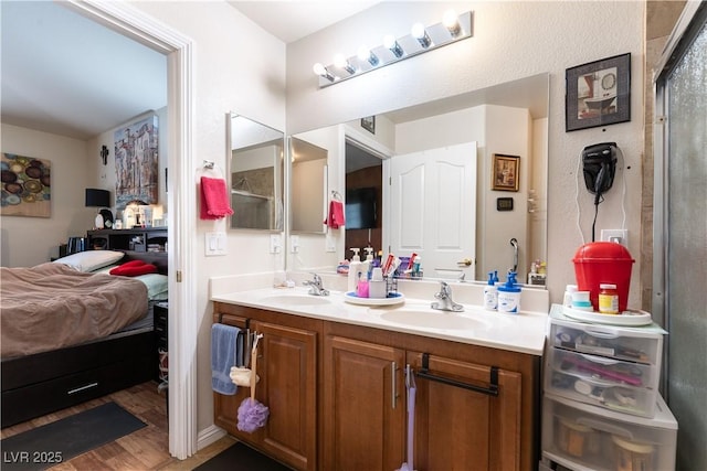 full bathroom featuring wood finished floors, a shower with door, a sink, and double vanity