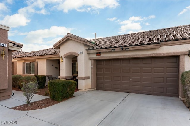 mediterranean / spanish home with a garage, driveway, a tiled roof, and stucco siding