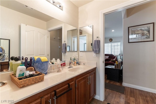 ensuite bathroom with ensuite bathroom, wood finished floors, visible vents, vanity, and baseboards