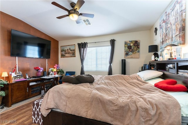 bedroom featuring lofted ceiling, wood finished floors, visible vents, and a ceiling fan