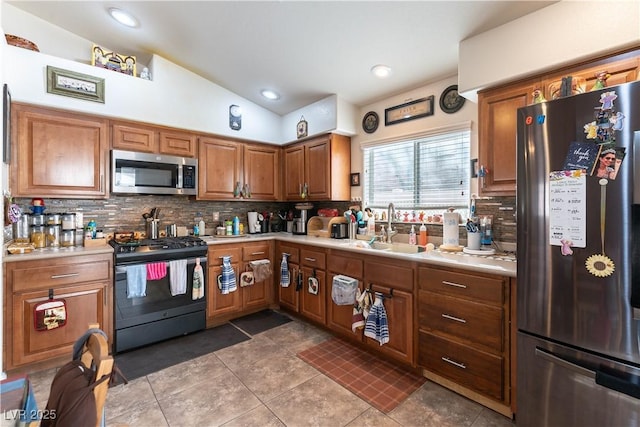 kitchen with vaulted ceiling, light countertops, appliances with stainless steel finishes, and a sink