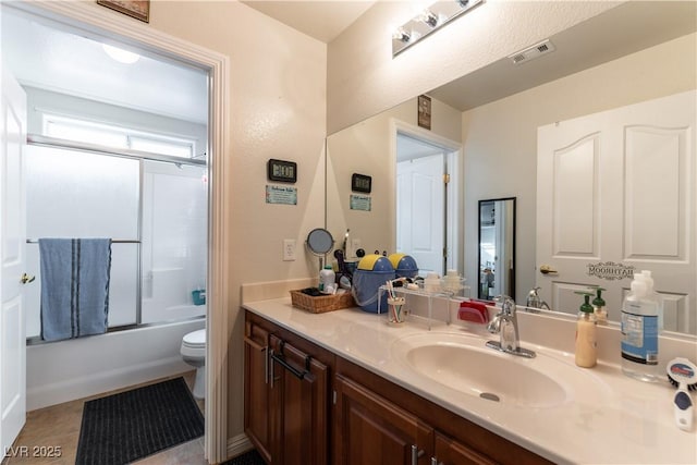 full bathroom featuring toilet, visible vents, bath / shower combo with glass door, and vanity