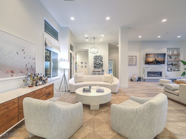 living room featuring light wood-type flooring, a premium fireplace, and recessed lighting