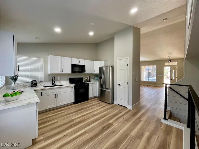 kitchen featuring light wood-type flooring, black appliances, white cabinetry, and a sink