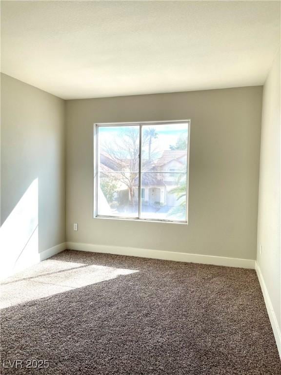 carpeted empty room featuring baseboards