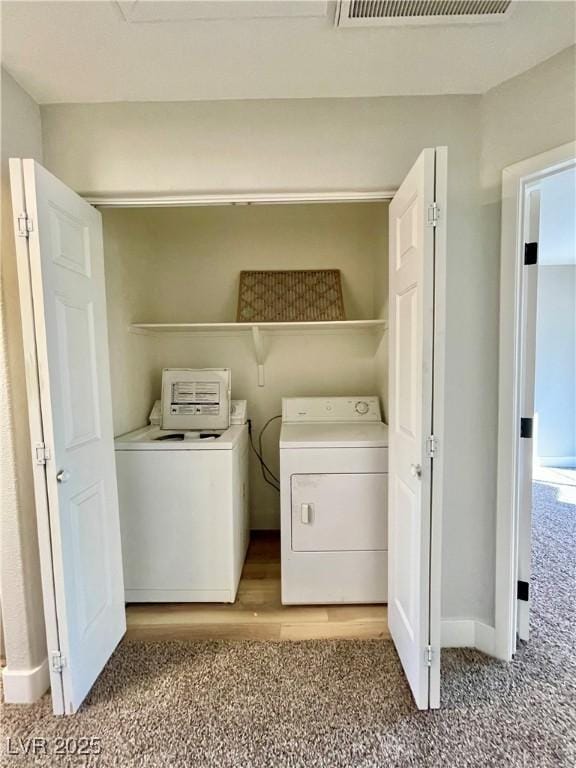 clothes washing area featuring washer and clothes dryer, visible vents, carpet flooring, laundry area, and baseboards