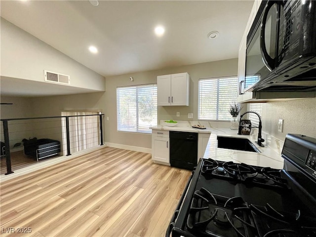 kitchen with black appliances, visible vents, white cabinets, and a sink