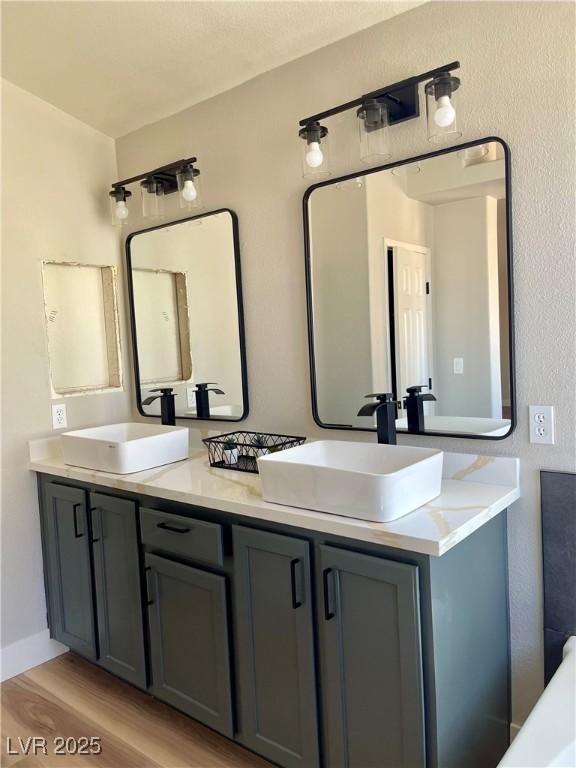 full bathroom featuring double vanity, wood finished floors, and a sink