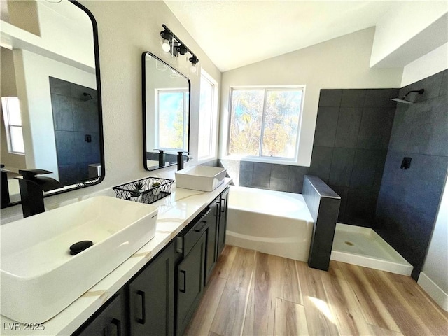 bathroom featuring lofted ceiling, a garden tub, a sink, and wood finished floors