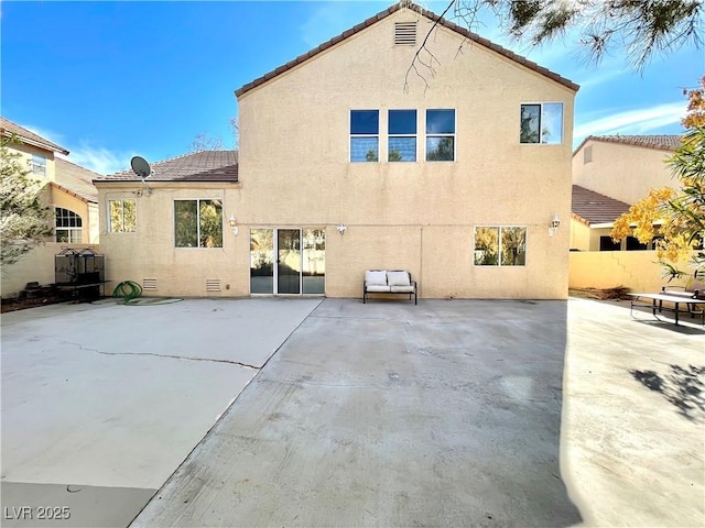 rear view of property featuring a tile roof, a patio, fence, and stucco siding