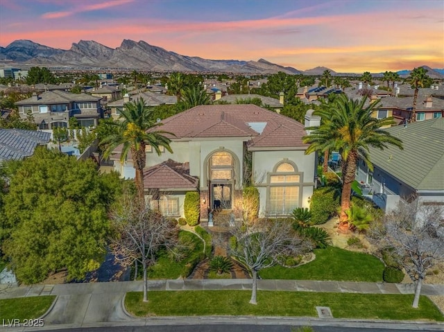 view of front of home featuring a residential view, a tile roof, a mountain view, and stucco siding