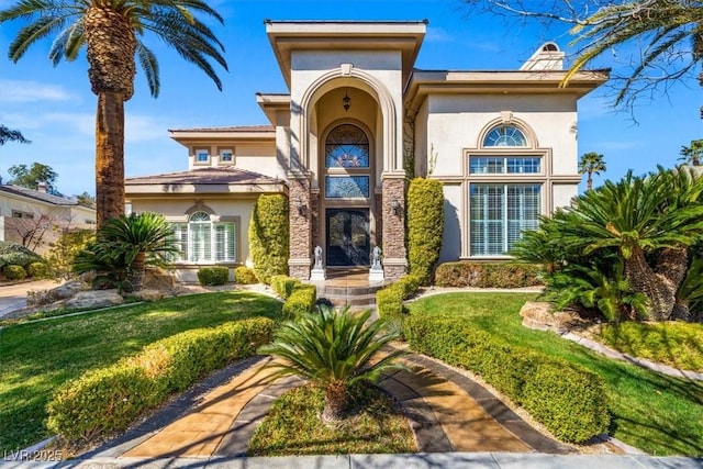 property entrance featuring a chimney, a lawn, and stucco siding