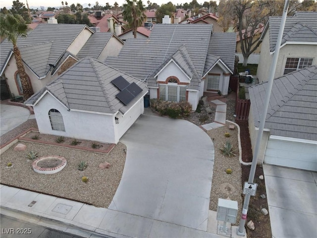 view of front of house with roof mounted solar panels, a tile roof, a residential view, and stucco siding