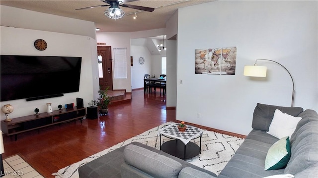 living area featuring ceiling fan with notable chandelier, wood finished floors, and baseboards