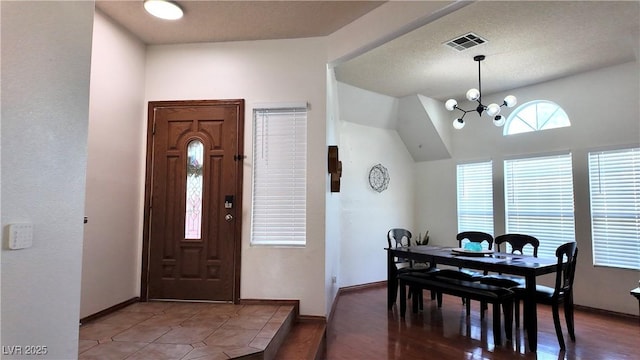 dining space with visible vents, an inviting chandelier, vaulted ceiling, wood finished floors, and baseboards