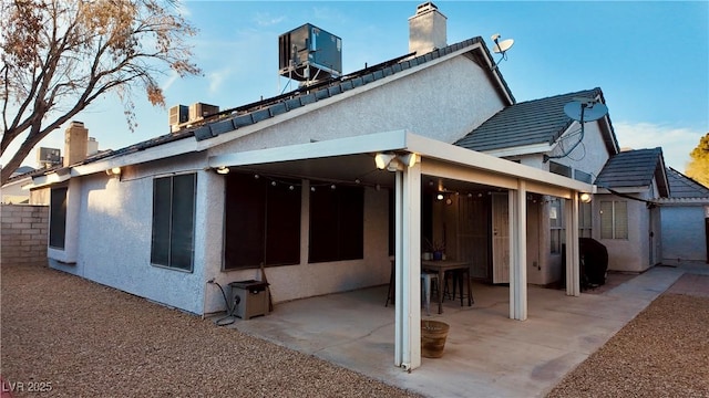 back of house with central AC, a patio, a chimney, and stucco siding