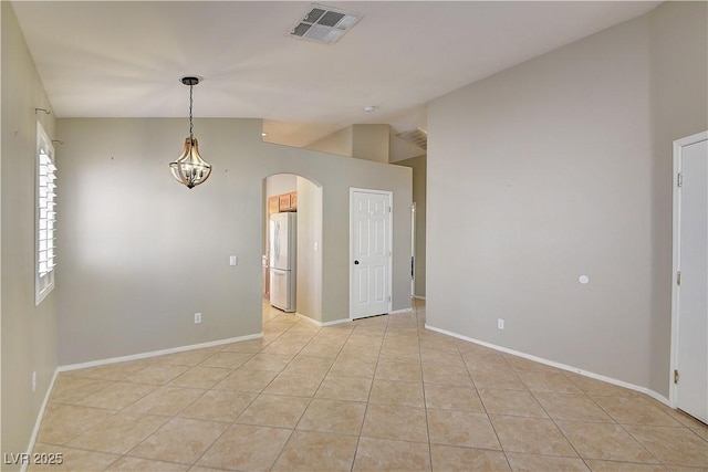 spare room with arched walkways, light tile patterned floors, lofted ceiling, visible vents, and baseboards