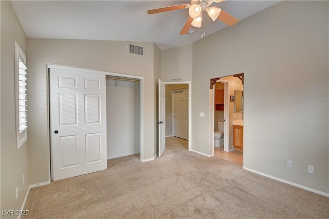 unfurnished bedroom featuring light colored carpet, visible vents, baseboards, vaulted ceiling, and a closet