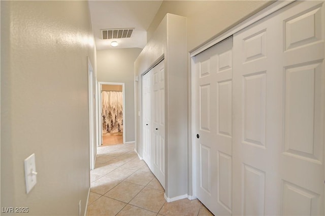 hall with visible vents, baseboards, and light tile patterned floors