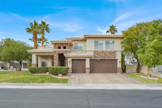 mediterranean / spanish-style home featuring a garage, driveway, stone siding, a tiled roof, and stucco siding