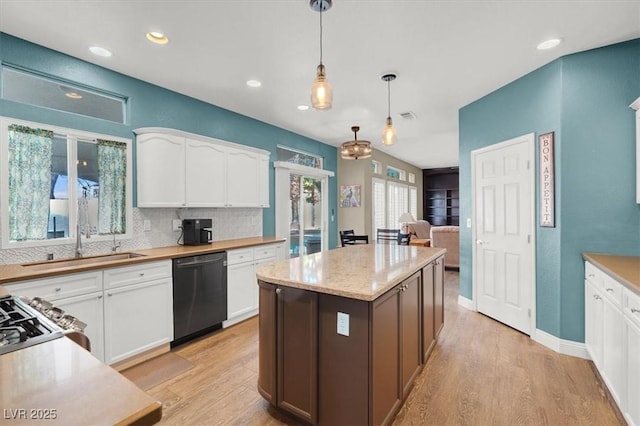 kitchen featuring white cabinetry, a center island, dishwasher, light wood finished floors, and decorative light fixtures