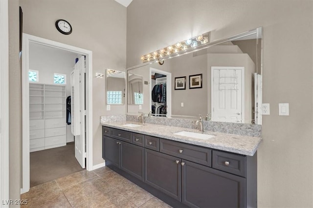 bathroom featuring double vanity, a spacious closet, and a sink