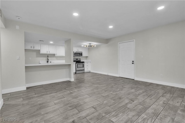 unfurnished living room featuring recessed lighting, wood finish floors, a sink, and baseboards