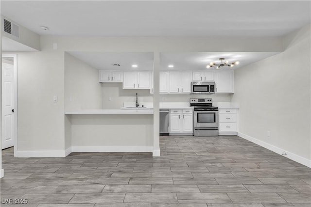 kitchen featuring appliances with stainless steel finishes, white cabinets, light countertops, and baseboards