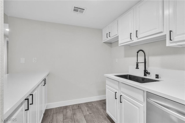 kitchen with a sink, visible vents, white cabinetry, light countertops, and stainless steel dishwasher