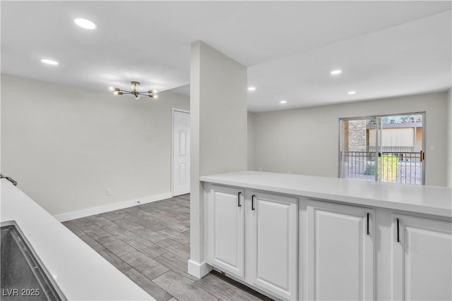 kitchen with wood tiled floor, light countertops, and white cabinetry