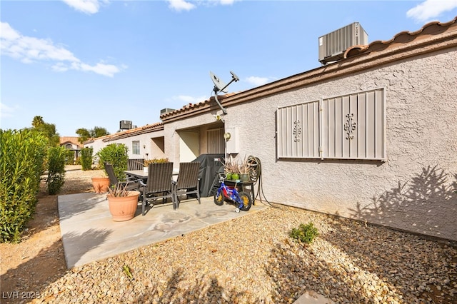 rear view of house featuring central AC unit, a patio, and stucco siding