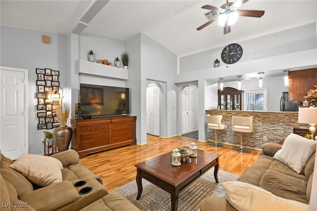 living room with ceiling fan, high vaulted ceiling, wood finished floors, and visible vents