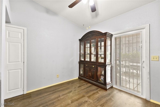 empty room with ceiling fan, dark wood-type flooring, and baseboards