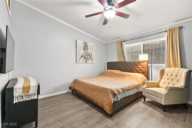 bedroom with ornamental molding, a ceiling fan, vaulted ceiling, wood finished floors, and baseboards