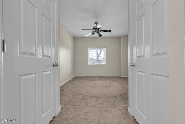 empty room featuring light carpet, ceiling fan, and baseboards