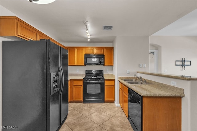 kitchen featuring light tile patterned flooring, a peninsula, a sink, black appliances, and brown cabinetry