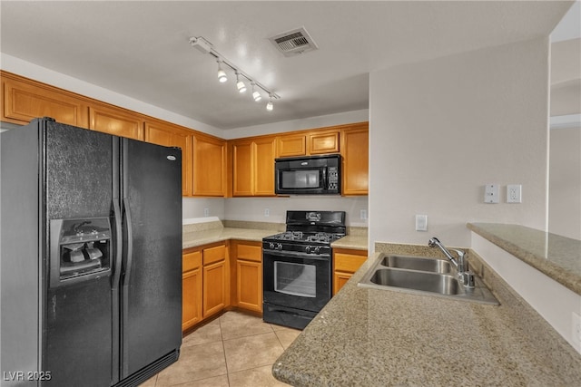 kitchen featuring light tile patterned floors, visible vents, brown cabinetry, black appliances, and a sink