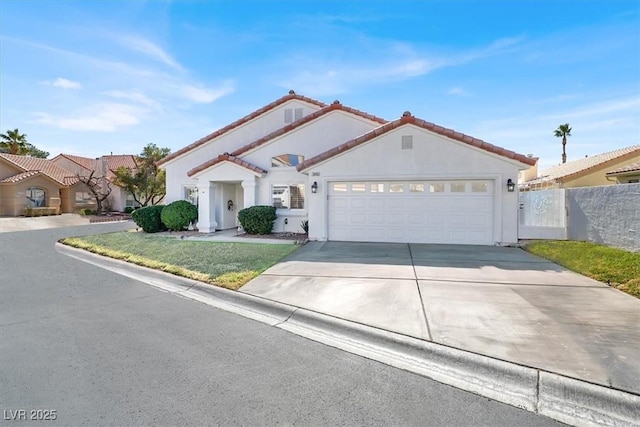 mediterranean / spanish house with concrete driveway, a tile roof, an attached garage, fence, and stucco siding