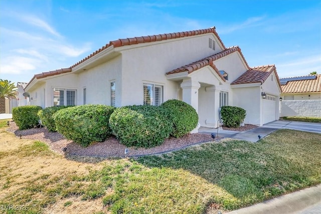 view of property exterior featuring a garage, a lawn, a tiled roof, and stucco siding