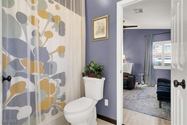 bathroom featuring toilet, wood finished floors, visible vents, and baseboards