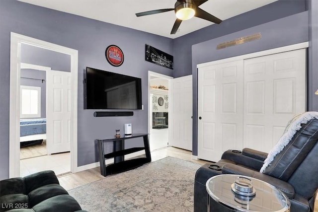 living room with ceiling fan, light wood-type flooring, and baseboards