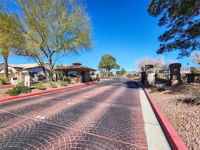 view of street featuring curbs, a gated entry, and a gate