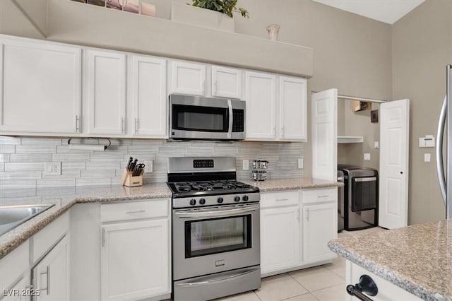 kitchen with appliances with stainless steel finishes, white cabinetry, decorative backsplash, and light tile patterned floors