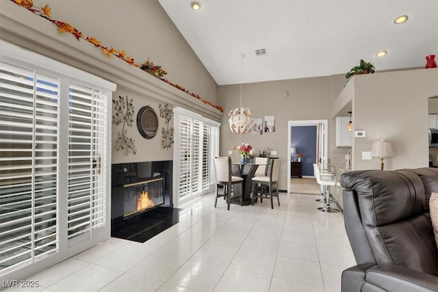 living area featuring light tile patterned floors, a glass covered fireplace, visible vents, and recessed lighting