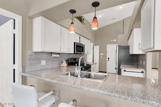 kitchen featuring a peninsula, white cabinetry, hanging light fixtures, appliances with stainless steel finishes, and decorative backsplash