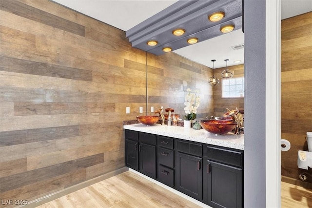 full bath featuring wood finished floors, visible vents, a sink, and double vanity