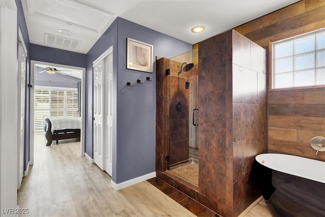 ensuite bathroom with wood finished floors, plenty of natural light, a shower stall, and visible vents