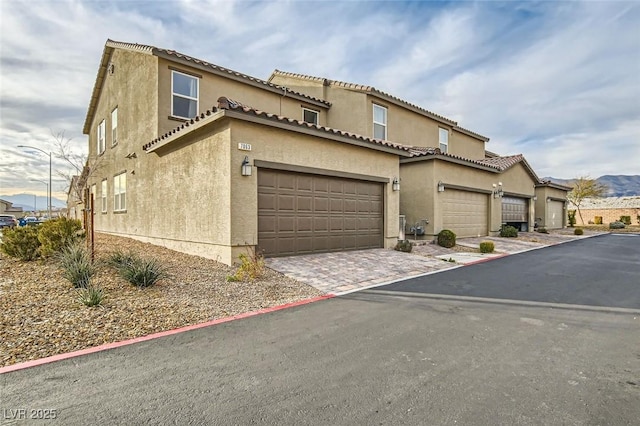 exterior space with decorative driveway, a tile roof, and stucco siding